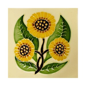 May include: A ceramic tile with a design of three yellow sunflowers with brown centers and green leaves on a cream background.