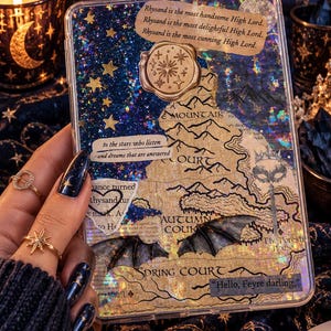 May include: A rectangular clear phone case featuring a collage of a map, holographic star patterns, and text including "Rhysand is the most handsome High Lord" and "to the stars who listen." It includes a gold wax seal and bat wing accents.