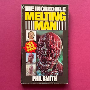 May include: A vintage paperback book titled "The Incredible Melting Man" with a gruesome, close-up image of a melting face on the cover. The title is in yellow and black, with the author's name, Phil Smith, at the bottom.