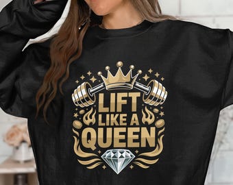 May include: Black sweatshirt featuring a gold and white graphic. The design includes a barbell, crown, diamond, and the text "LIFT LIKE A QUEEN". The graphic is surrounded by stars and flames.