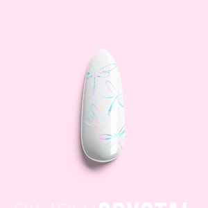May include: A white oval-shaped fake nail with a design of iridescent blue and pink dragonflies.