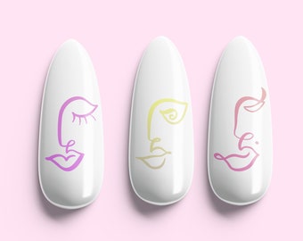 May include: Three white oval-shaped nail tips with abstract face designs in pink, yellow, and blue. The nail tips are arranged horizontally on a pink background. The text "SIMPLYCRYSTAL nails" is below the nail tips.