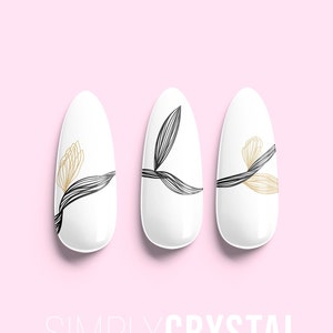 May include: Three white oval-shaped artificial nails with a floral design. The nails have black and gold lines forming a leaf and flower pattern. The text "SIMPLYCRYSTAL nails" is at the bottom of the image.