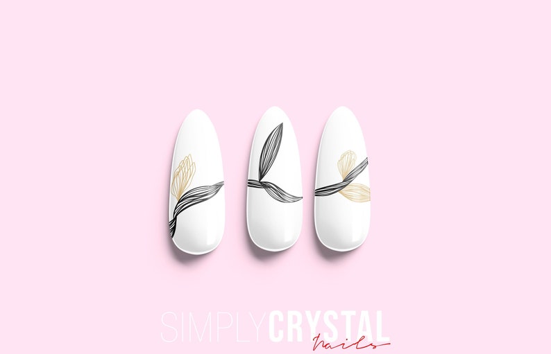 May include: Three white oval-shaped artificial nails with a floral design. The nails have black and gold lines forming a leaf and flower pattern. The text "SIMPLYCRYSTAL nails" is at the bottom of the image.