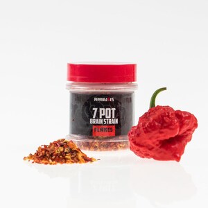 May include: A small glass jar with a red lid filled with red pepper flakes. The jar has a black label that reads "Pepper Joe's 7 Pot Brain Strain Flakes". A red 7 Pot Brain Strain pepper is next to the jar.