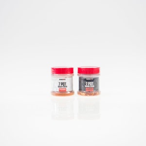 May include: Two small glass jars with red lids containing 7 Pot Brain Strain pepper flakes and powder. The jars are labeled "7 Pot Brain Strain" with "Flakes" and "Powder" printed below. The jars are on a white surface.