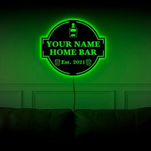 May include: Green neon sign with a black background that reads "YOUR NAME HOME BAR Est. 2021" with a bottle and two glasses icons.