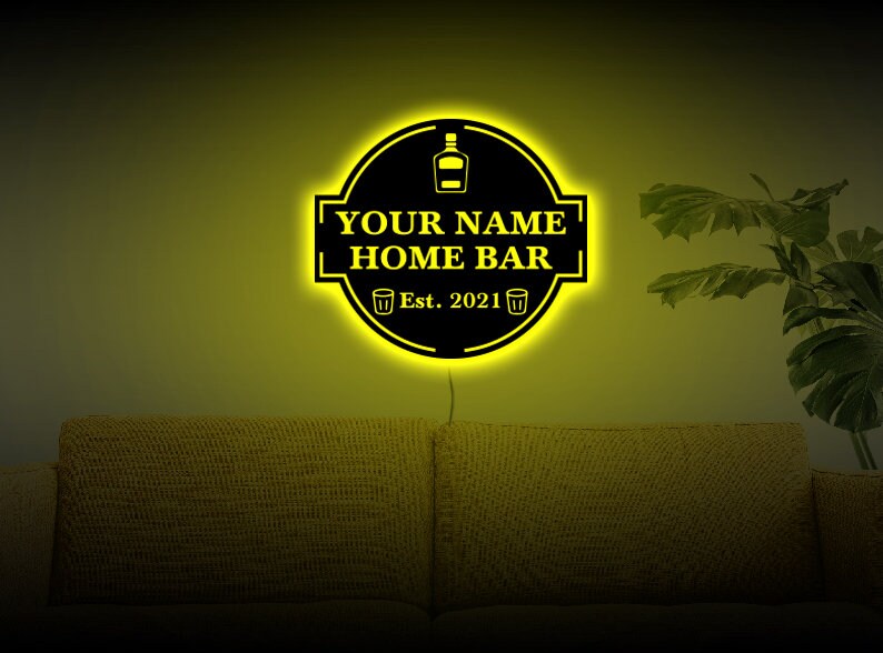 May include: A yellow neon sign with a black background that reads "YOUR NAME HOME BAR Est. 2021". The sign has a bottle and two shot glasses on it.