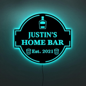 May include: A black and blue neon sign with the text "JUSTIN'S HOME BAR Est. 2021" and two shot glass icons.