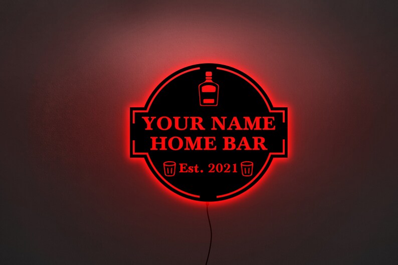 May include: Black and red illuminated sign with the text "YOUR NAME HOME BAR Est. 2021" and a bottle and two shot glasses.