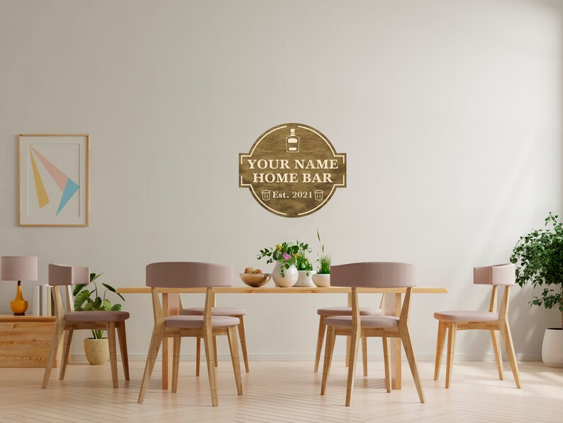 May include: A wooden sign with the text "YOUR NAME HOME BAR Est. 2021" and a bottle and two glasses icon. The sign is hanging on a white wall in a dining room with a wooden table and chairs.