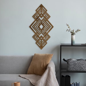 May include: A wooden geometric wall art piece with a diamond pattern in shades of brown. The art is mounted on a light blue wall above a gray couch with a brown throw blanket and a brown pillow.