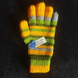 May include: Yellow and green striped knitted gloves with a small blue crocheted flower attached to a tag that reads "creaciones_nuditos tejido artesanal".