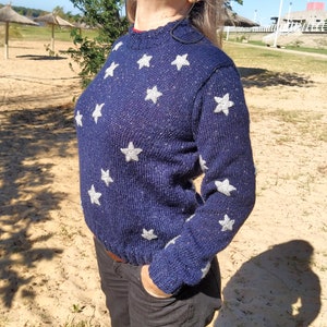 May include: A navy blue sweater with silver glitter and white star appliques.