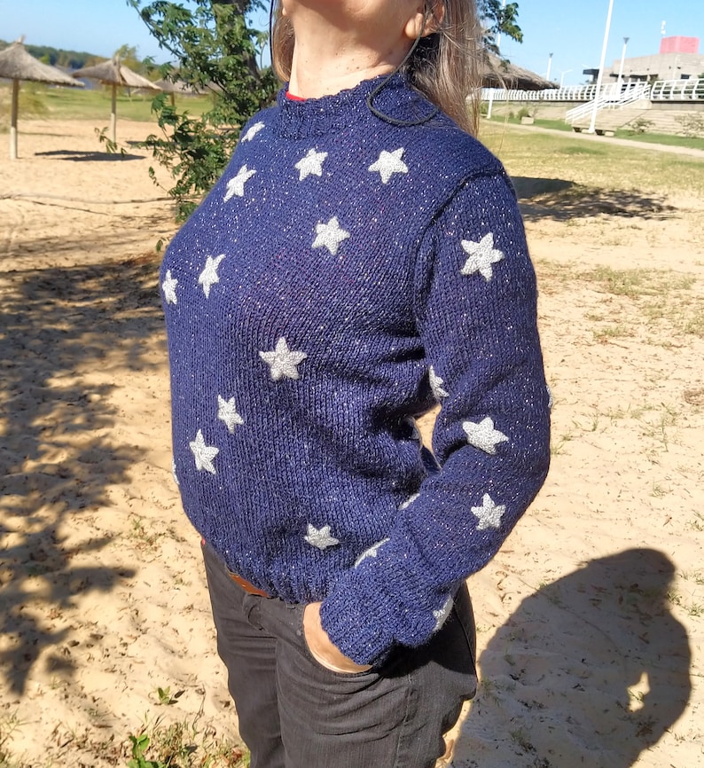May include: A navy blue sweater with silver glitter and white star appliques.