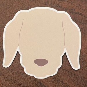 May include: A simple illustration of a light brown dog's head with a brown nose.