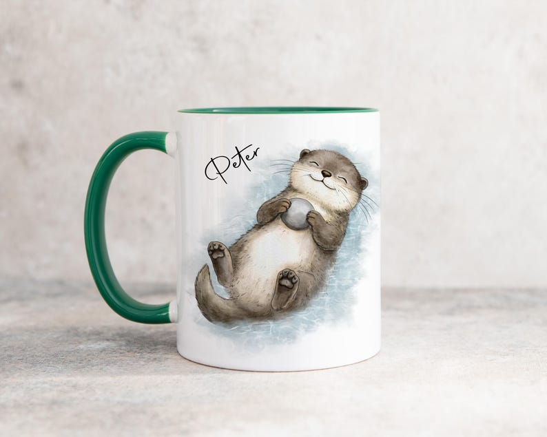 Pu&ograve; includere: Una tazza in ceramica bianca con manico e interno verde scuro. La tazza presenta un'illustrazione in stile acquerello di una lontra marrone che galleggia sulla schiena tenendo una piccola pietra grigia. Il nome Peter &egrave; scritto in nero sopra.