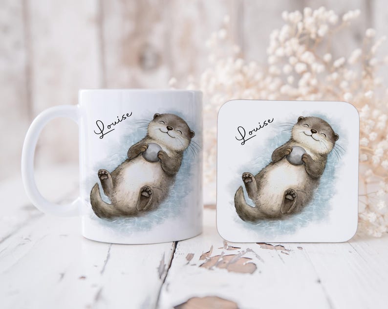 Pu&ograve; includere: Una tazza in ceramica bianca e un sottobicchiere quadrato, entrambi con un'illustrazione ad acquerello di una lontra marrone che galleggia sulla schiena tenendo una piccola pietra grigia. Il nome Louise &egrave; scritto in corsivo nero sopra l'animale.