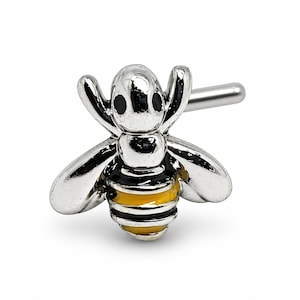 Peut inclure: Un bijou de nez en forme d'abeille argentée avec des détails noirs et jaunes. L'abeille présente des ailes et un dard. Le bijou est conçu pour être inséré dans la narine.