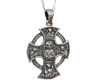 May include: A silver-toned metal cross pendant on a delicate chain. The cross features a circular frame with intricate embossed religious figures and iconography in the center and at each of the four points, finished with a polished silver bail.
