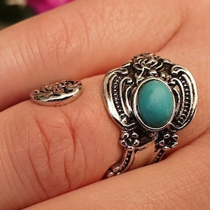 Könnte beinhalten: Ein silberner Ring mit einem verzierten Design und einem türkisfarbenen Stein. Der Ring ist verstellbar und kann an verschiedenen Fingern getragen werden.