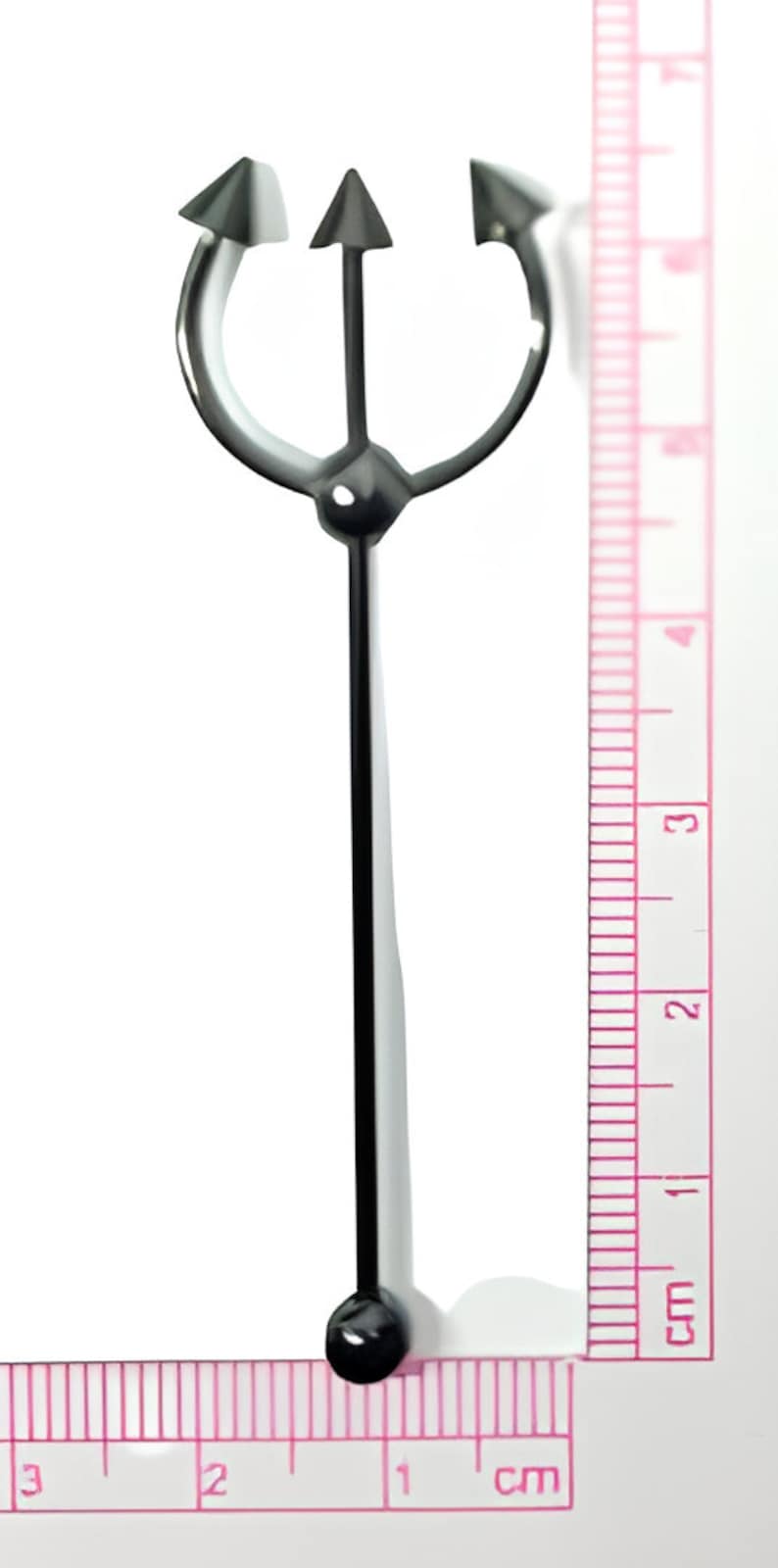 May include: A black metal trident with three points, measuring approximately 5 cm in length. The trident has a round ball at the bottom.