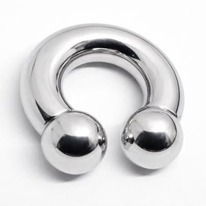 May include: A polished, silver-colored horseshoe-shaped body jewelry piece. The ends of the curved bar terminate in two spherical balls. The jewelry is designed with a smooth, reflective surface.