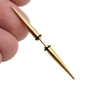 May include: Gold-colored metal ear piercing with a pointed tip. The piercing is made of two pieces that screw together.
