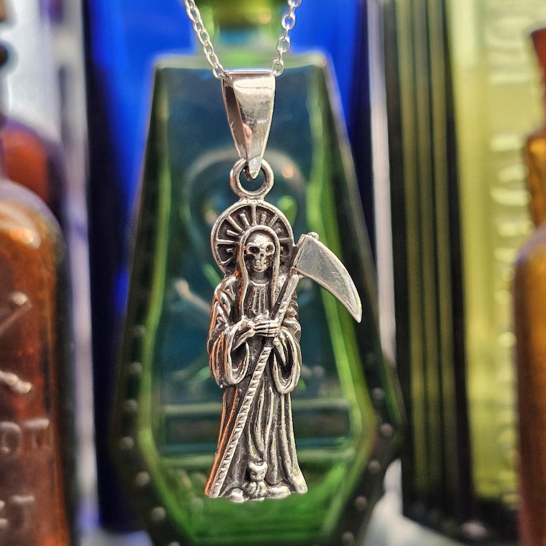Pu&ograve; includere: Collana con ciondolo in argento raffigurante una rappresentazione dettagliata della Morte che tiene una falce. Il ciondolo &egrave; su una catena d'argento.