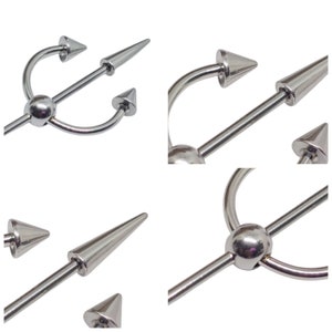 May include: A silver industrial barbell body piercing jewelry with a trident design. The barbell features a long, straight bar with a central sphere and three pointed ends. The ends are cone-shaped and the overall design is symmetrical.