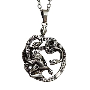Könnte beinhalten: Silberne Halskette mit einem Anhänger, der eine detaillierte Darstellung von Medusa zeigt, die griechische mythologische Figur mit Schlangenhaaren.