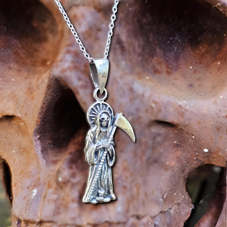 Pu&ograve; includere: Collana con ciondolo in argento che rappresenta una rappresentazione dettagliata della Morte che tiene una falce. Il ciondolo &egrave; appeso a una catena d'argento.