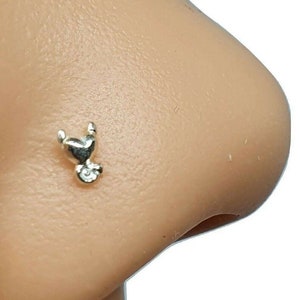 Può includere: Un anello per il naso in argento con un design a forma di cuore. L'anello è piccolo e delicato, perfetto per aggiungere un tocco di brillantezza a qualsiasi look.