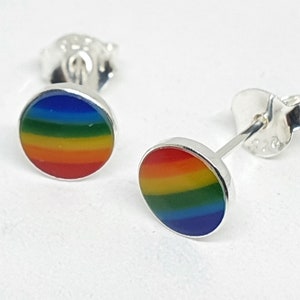 Könnte beinhalten: Ein Paar silberne Ohrstecker mit einem Regenbogen-Emaille-Design. Die Ohrringe sind rund und haben einen silbernen Stift und eine Schmetterlings-Rückseite.