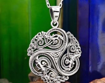 May include: A silver-toned pendant featuring an intricate circular design with three intertwined, stylized animal figures and knotwork patterns. The pendant is suspended from a matching silver-toned chain link necklace, showcasing a polished metallic finish.