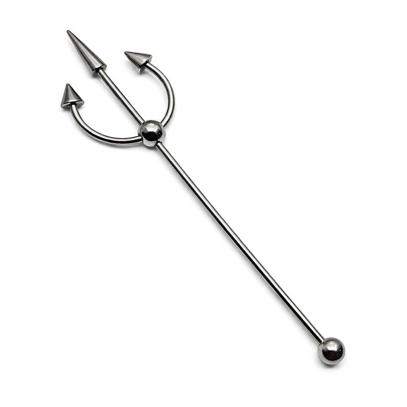 May include: A silver-colored industrial barbell body piercing jewelry. The barbell features a trident design at the top with three pointed tips and a ball at the bottom. The jewelry is made of a shiny, metallic material.
