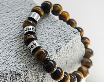 May include: A brown and gold tiger's eye beaded bracelet with silver beads that have the names "Jack" and "Bey" engraved on them.