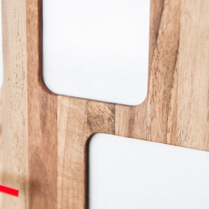 May include: A wooden wall clock with a red second hand and white clock faces. The clock has a modern design with a minimalist aesthetic.