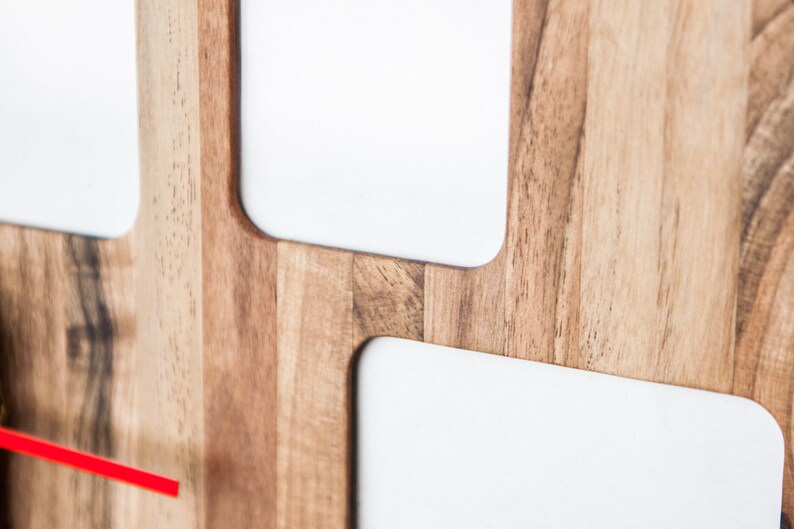 May include: A wooden wall clock with a red second hand and white clock faces. The clock has a modern design with a minimalist aesthetic.