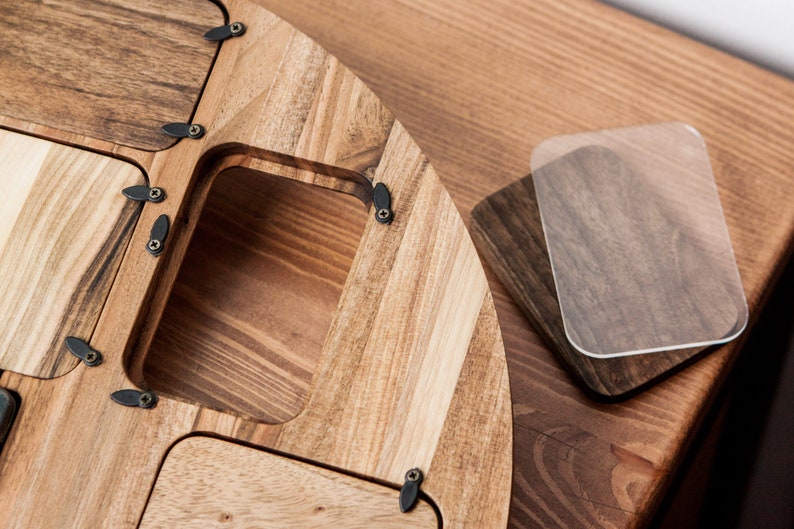 May include: A wooden tray with multiple compartments and a hinged lid. The tray is made of light brown wood with a natural grain pattern. The lid is secured with small black metal hinges and screws.