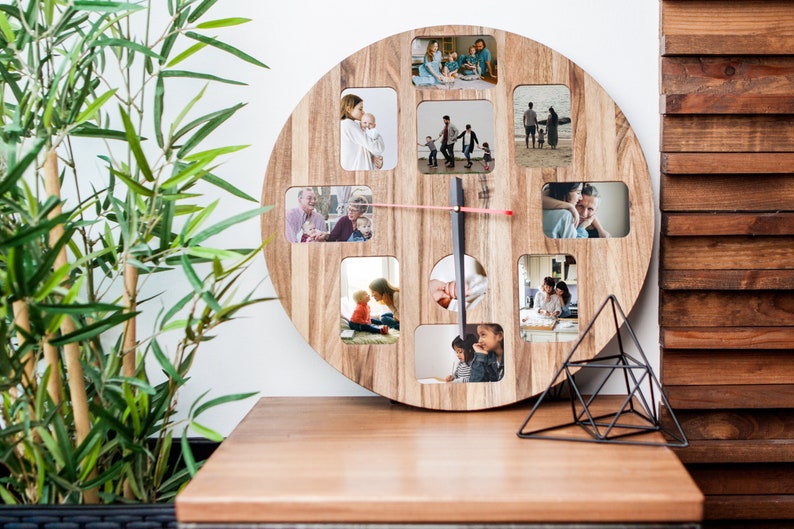 May include: A round wooden clock with a photo frame design. The clock has 12 photo slots, each displaying a different family photo. The clock is on a wooden table with a black metal geometric stand.