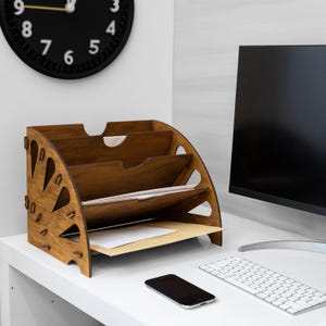 May include: A white ceramic mug with a black handle and the text "But First, Coffee" in a bold, black font. The mug is set against a blurred background, suggesting a cosy setting.