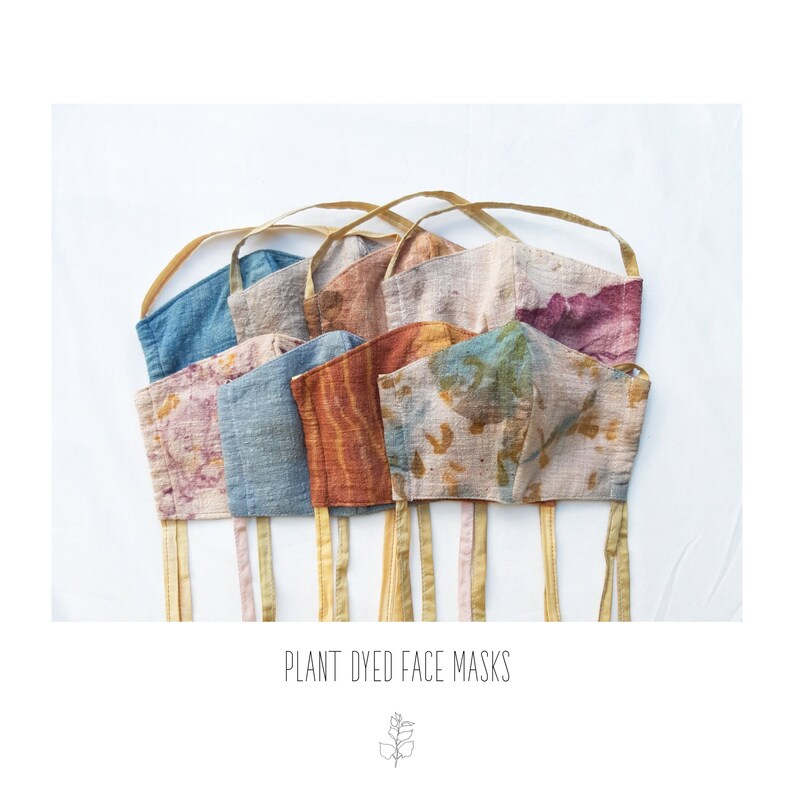 May include: A collection of plant-dyed face masks in various colors, including blue, pink, orange, and green. Each mask has a unique pattern and is displayed with gold-colored straps. The text "PLANT DYED FACE MASKS" is at the bottom.