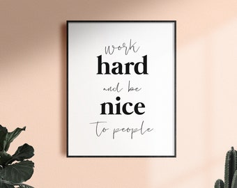 Puede incluir: Impresión de una cita motivacional en blanco y negro en un marco negro sobre una pared rosa claro. La cita dice "trabaja duro y sé amable con la gente".