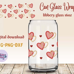 May include: A clear glass can with a design of pink and gold hearts. The can is 16 ounces and is labeled "Can Glass Wrap" and "libbery glass 16oz".