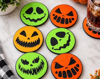 May include: A set of six circular drink coasters featuring vibrant orange and neon green backgrounds with black printed jack-o'-lantern faces. Each coaster displays a unique spooky expression, including jagged teeth, wide grins, and triangular eyes.