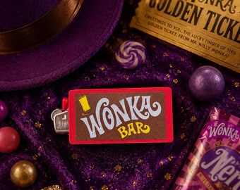 May include: A rectangular red lighter featuring a brown label with the white text Wonka Bar and a small yellow top hat icon. The lighter is surrounded by a purple top hat, a gold Wonka Golden Ticket, a purple Nerds candy box, and various candies.