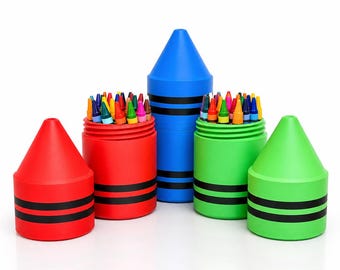 May include: A set of three cylindrical crayon-shaped storage containers in red, blue, and green. The red and green containers are open, revealing assorted colorful wax crayons inside. Each container features two horizontal black stripes near the base.
