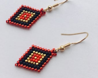 Può includere: Un paio di orecchini a forma di diamante, realizzati con perline rosse, nere e dorate. Gli orecchini hanno ganci dorati.