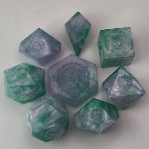 May include: Set of eight green and purple dice with various designs. The dice are made of a translucent material and have a marbled effect.